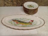 a plate with a fish painted on it next to a stack of plates