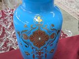 un vase bleu posé sur une table recouverte d'une nappe rouge