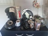 une commode noire sur laquelle sont posés un téléphone, des tasses à café et d'autres objets