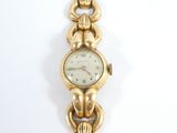 a gold watch with a chain around it on a white surface