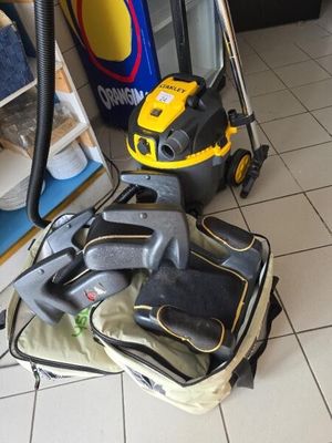 un aspirateur jaune et noir posé sur un sol carrelé blanc