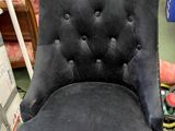 a black chair with a buttoned back in a room