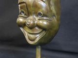 a close up of a statue of a smiling face on a marble base