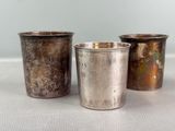 three silver cups sitting next to each other on a table
