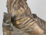 bronze statue of a woman sitting on a rock with a flower in her hand