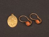 two gold earrings and a gold coin on a black surface