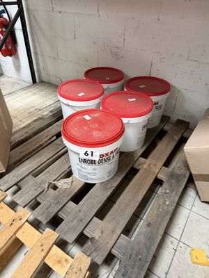 several buckets of paint sitting on a pallet in a room
