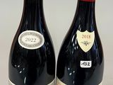 two bottles of red wine sitting next to each other on a table