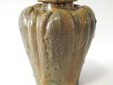 un vase marron avec un couvercle, posé sur une surface blanche