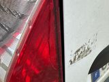 a white car with rust on the side of it ' s tail lights