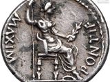 a silver coin with a woman sitting on a chair in front of a window