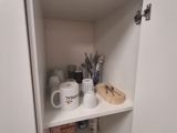 a white cupboard with a cup and mugs on it