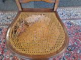 a wooden chair with a wicker seat on a rug