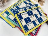 a pile of bingo cards on a table next to a bottle of wine