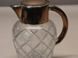 a glass pitcher with a metal lid on a table