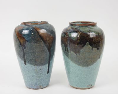 deux vases posés l'un à côté de l'autre sur une surface blanche