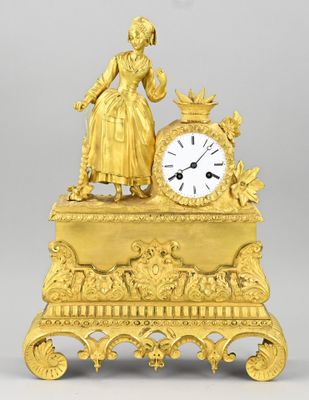 a gold clock with a woman standing on top of it