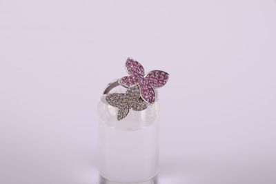 a close up of a pink butterfly ring on a clear glass