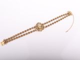 a close up of a gold chain bracelet with a cross on it