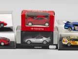 quatre modèles différents de petites voitures exposés dans des vitrines posées sur une surface blanche