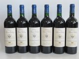 six bottles of red wine are lined up on a table