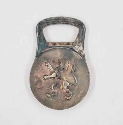 a metal bottle opener with a lion on it
