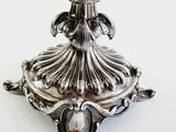 a silver bowl on a stand on a white surface