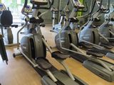 rows of stationary exercise bikes in a gym with a clock on the wall
