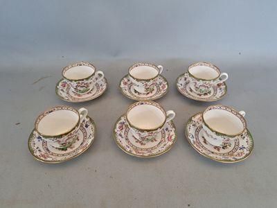 six tasses et soucoupes ornées de motifs floraux, posées sur une table