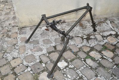 a broken bicycle frame sitting on the ground next to a wall