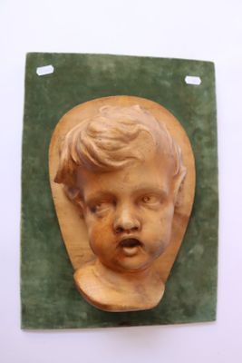 une sculpture en bois représentant le visage d'une femme, posée sur un tapis vert