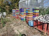 un tas de caisses posées dans l'herbe, près d'une clôture