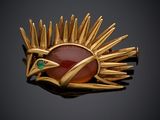 une broche en or ornée d'une pierre rouge entourée de pointes