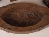 three wooden ashtrays with carved leaves on them on a white surface