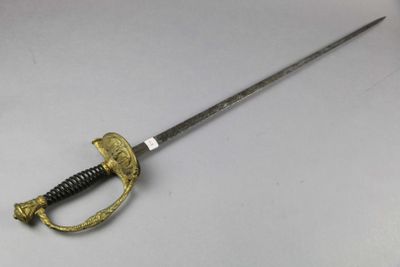 a close up of a sword on a table with a white background