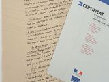 an old document with a handwritten letter on it next to a piece of paper