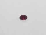 a close up of a red garnet stone on a white surface