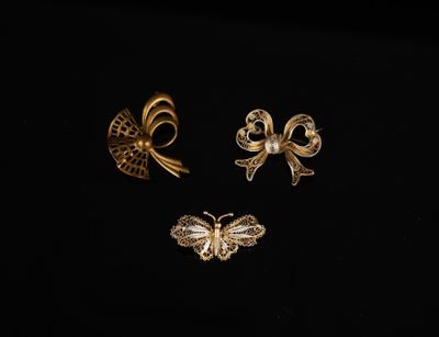 trois broches en or et un papillon sur fond noir
