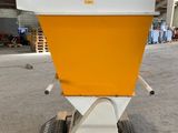 a yellow and white spreader sitting on top of a wooden pallet