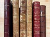 Plusieurs vieux livres sont alignés sur une étagère posée sur une table
