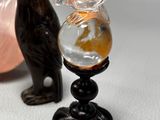 a bird figurine next to a glass with a gold fish in it