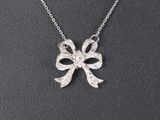 a close up of a necklace with a bow on it