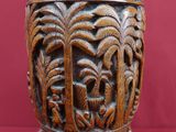 un vase en bois orné de sculptures sur un fond rouge