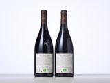 two bottles of red wine sitting on top of a table