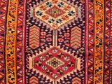 a red and orange rug with a geometric design