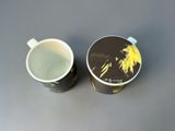a cup with a lid sitting next to a cup with a picture on it