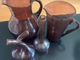 three brown vases sitting on a table with figurines