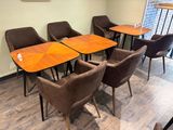 de nombreuses chaises et tables dans une pièce où est accroché un tableau au mur
