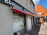 a building with a sign that says brisssiede and a bench on the sidewalk in front of it