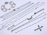 various silver necklaces and bracelets laid out on a white surface